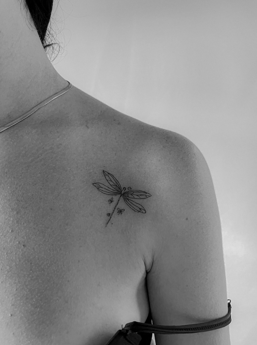 Tatuaje fineline libélula en clavícula